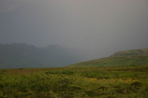 2003 Jeep TJ - A vast, open landscape with rolling green hills and a stormy sky overhead.