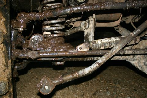 2003 Jeep TJ - Close-up of heavily muddied suspension and steering parts on a vehicle after off-roading.