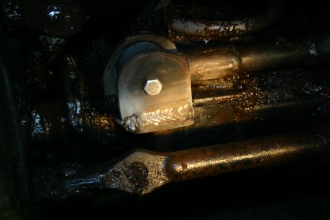 2003 Jeep TJ - A close-up view of a greasy suspension component, showing a hex bolt and weld repairs.