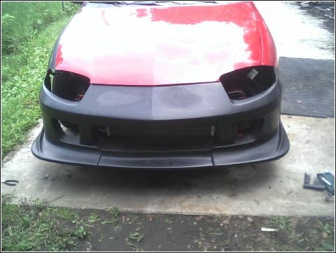 2005 Chevrolet Cavalier - The front of a red car is shown with a new black bumper and no headlights.