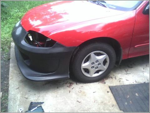 2005 Chevrolet Cavalier - The front of a red 2005 Chevrolet Cavalier shows an aftermarket bumper and a missing headlight assembly.