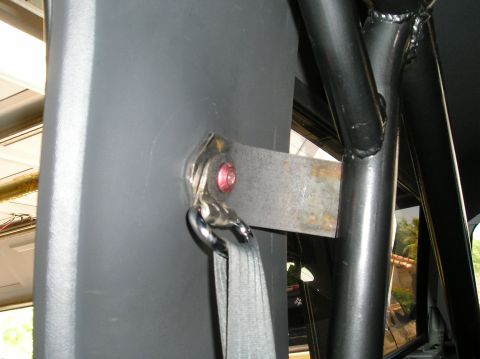 1993 Ford Bronco - A metal bracket is bolted to a gray interior panel, holding a seatbelt.