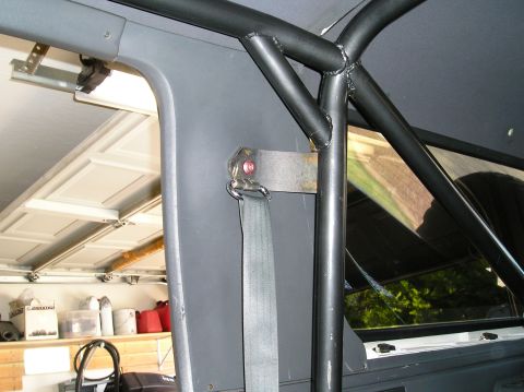 1993 Ford Bronco - Interior view of a vehicle's roll cage and seatbelt, with a garage door in the background.