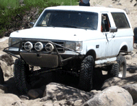 1993 Ford Bronco - This modified Ford Bronco navigates a rocky trail, showing its off-road capabilities.