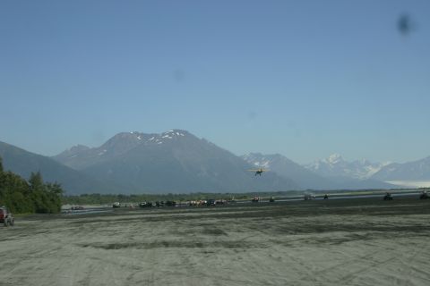 2003 Jeep TJ - A scenic view of mountains with a small plane and various vehicles on a sandy plain.