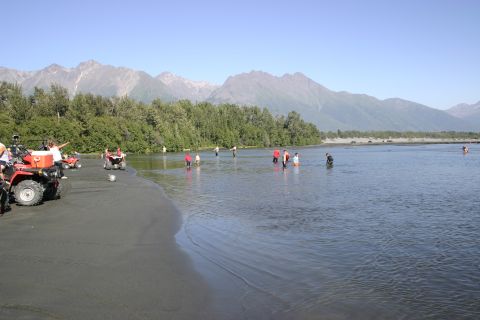2003 Jeep TJ - People and ATVs gather on a sandy shore with a river and mountains in the distance.