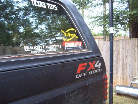 1988 Ford Bronco - A black 1988 Ford Bronco is shown from the rear quarter panel, off-road decals and various stickers on the rear window.