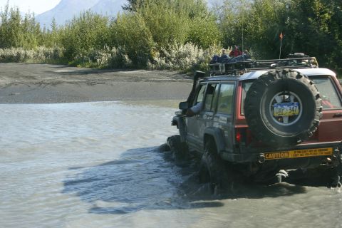 2003 Jeep TJ - Two Jeep Cherokee XJs navigate a water crossing with trees and mountains in the background.