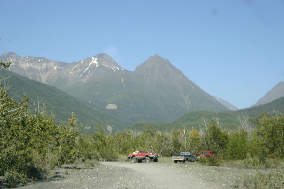 Three off-road vehicles parked on a dirt road with mountains in the background