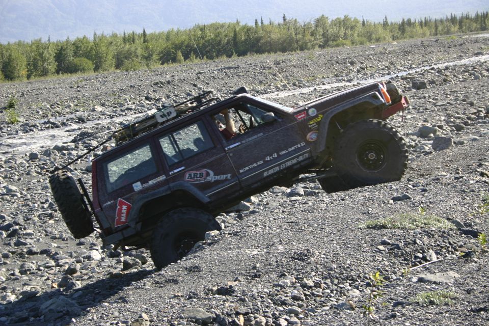 Dark red Jeep Cherokee XJ climbing a rocky slope, side view