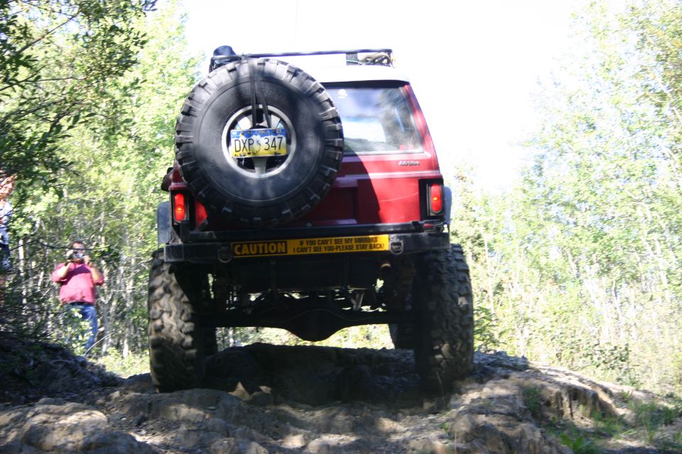 Red 2003 Jeep TJ with a spare tire on the back, driving on a dirt trail