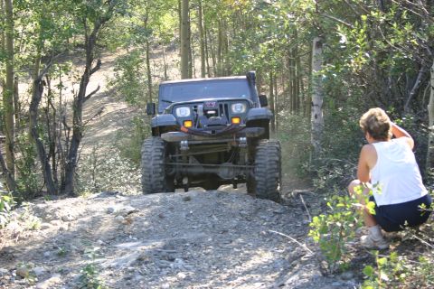 2003 Jeep TJ - A Jeep Wrangler navigates a rocky trail through a wooded area.