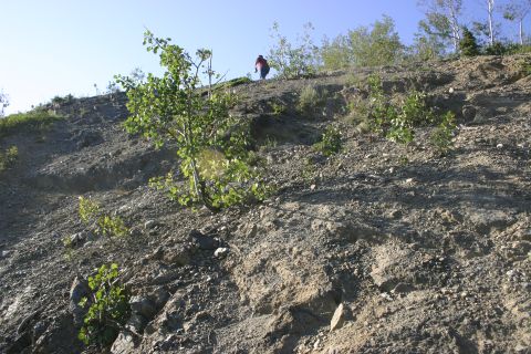 2003 Jeep TJ - A person walks up a steep, rocky slope with sparse vegetation under a clear blue sky.