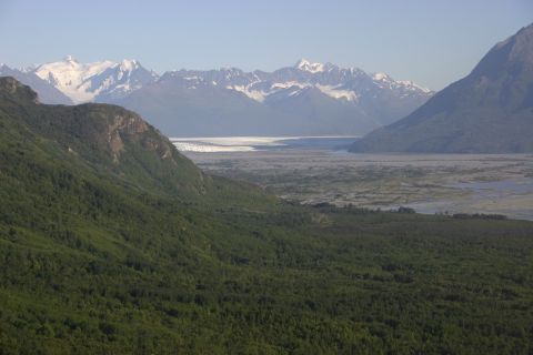 2003 Jeep TJ - A vast mountain landscape unfolds, a glacier in the distance and lush green forests covering the slopes.