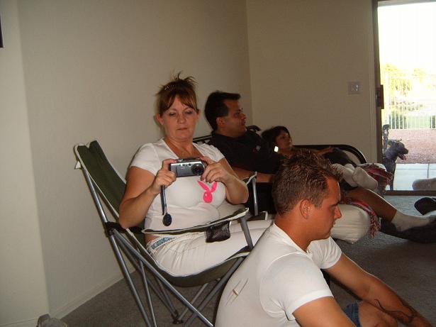 Woman with camera in folding chair and others sitting in a living room; no vehicle shown
