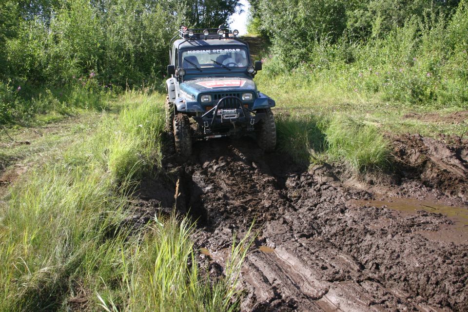 Jeep TJ driving through mud on a trail. Has 'KODIAK OFFROAD' on the windshield banner