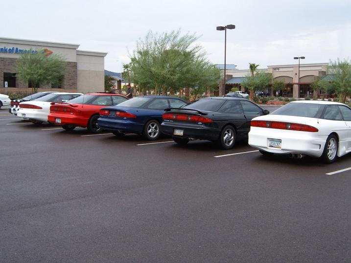 Row of Ford Probe coupes parked rear-out in front of a Bank of America strip mall