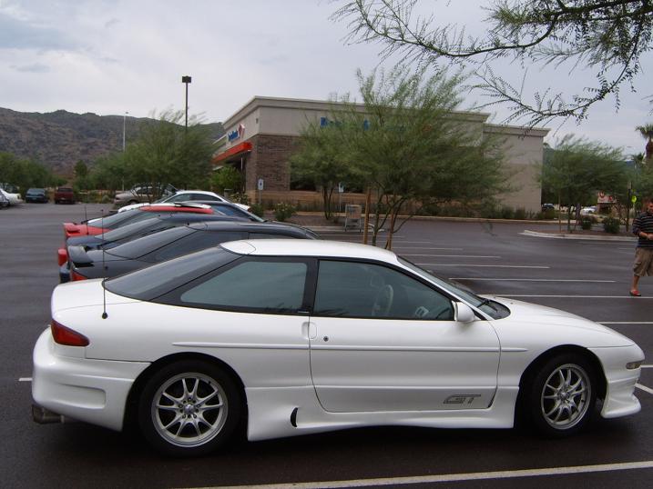 White Ford Probe GT coupe, driver side profile, multi-spoke wheels, parked at a mountain-backed lot