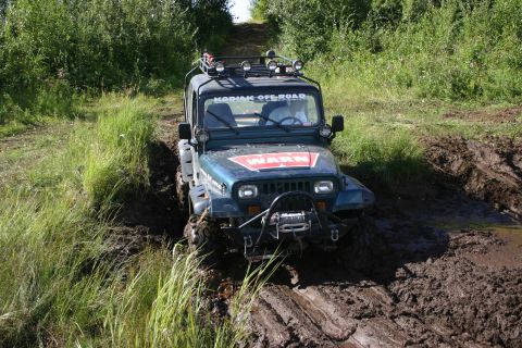 2003 Jeep TJ - Jeep Wrangler TJ navigating a muddy off-road trail with a winch and roof rack.