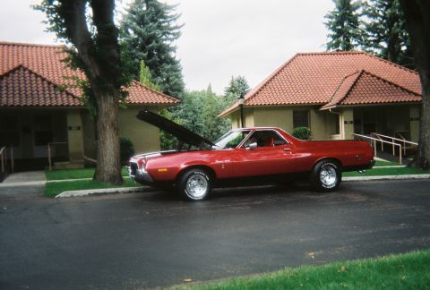 1972 Ford Ranchero - A red coupe utility vehicle is parked in front of a building with its hood open, showing off its engine bay.