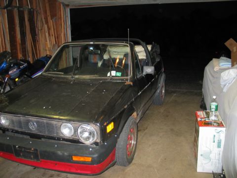 1986 Volkswagen Cabriolet - Black 1986 Volkswagen Cabriolet with red trim on the front bumper, parked indoors.