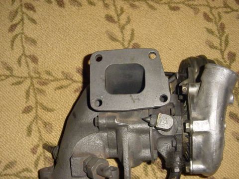 1995 Ford Mustang - Close-up of a turbocharger part, showing its metallic components and flange.
