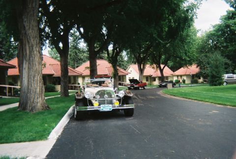 1972 Ford Ranchero - An antique convertible is parked on a paved road in front of a row of houses.