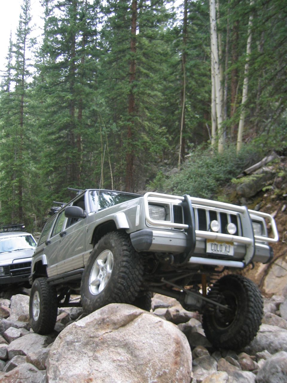 Gray 1997 Jeep Cherokee navigating a rocky trail with a bull bar