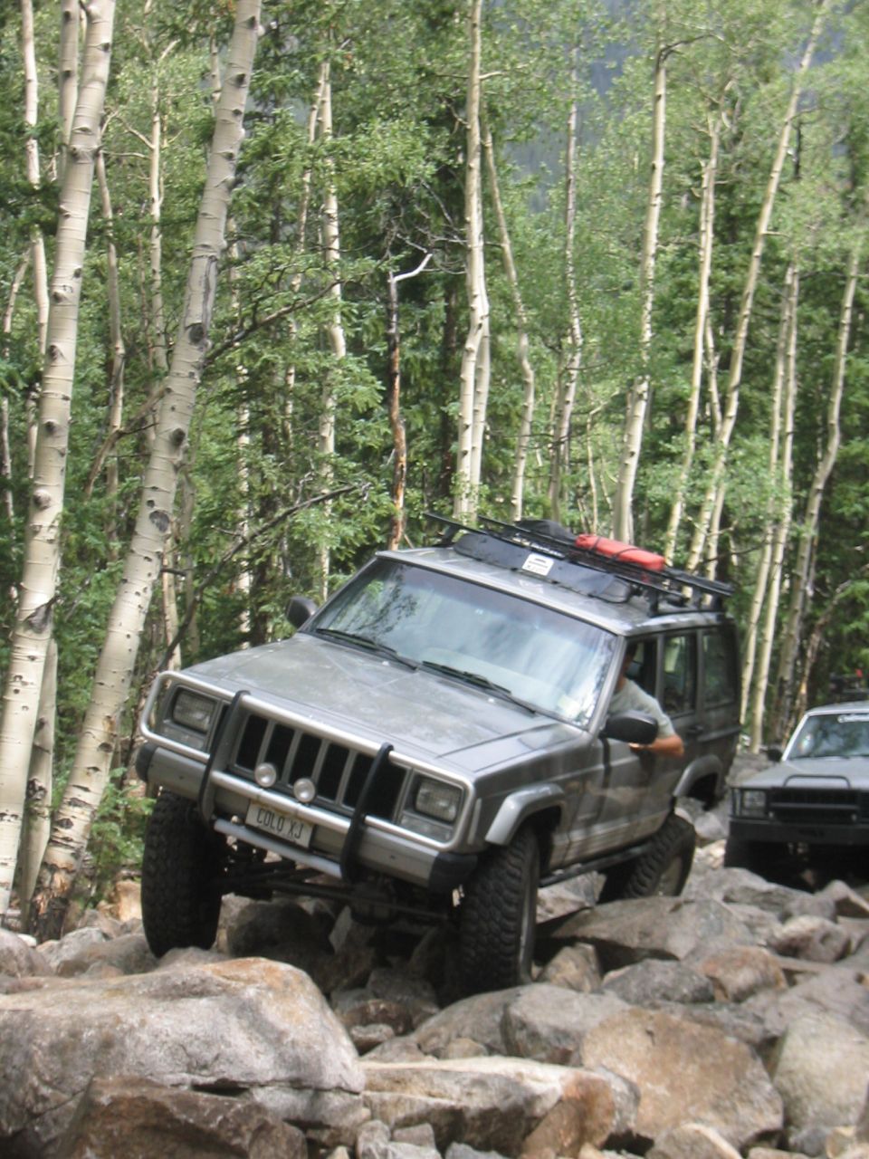 1997 Jeep Cherokee XJ navigating a rocky trail with another Jeep visible behind it