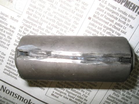 1992 Ford Bronco - A metal part is shown on top of a newspaper with visible text.