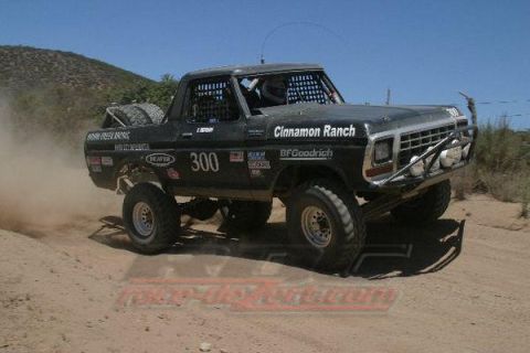 1990 Ford Bronco - black off-road race truck numbered 300 with Cinnamon Ranch decals powers through a dusty desert course.