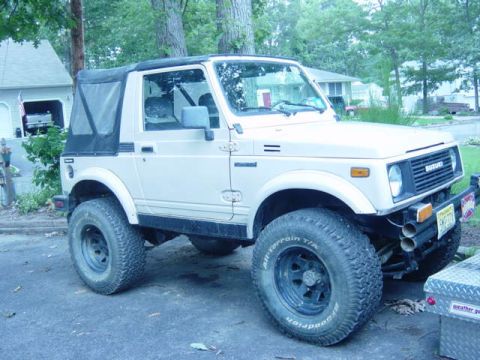 1987 Suzuki Samurai - This 1987 Suzuki Samurai features a tan exterior and a black soft top, shown from the front three-quarter angle.