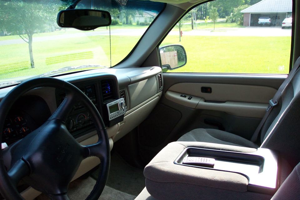 Tan interior of a GMC SUV showing steering wheel, dash-mounted satellite radio, and center console.