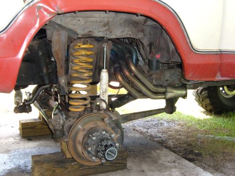 1978 Ford Bronco - Close-up of the front suspension and exhaust system on a 1978 Ford Bronco, showing custom headers and yellow coil springs.