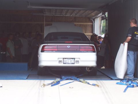 1990 Ford Probe - A 1990 Ford Probe is positioned on a dynamometer inside a garage with onlookers.