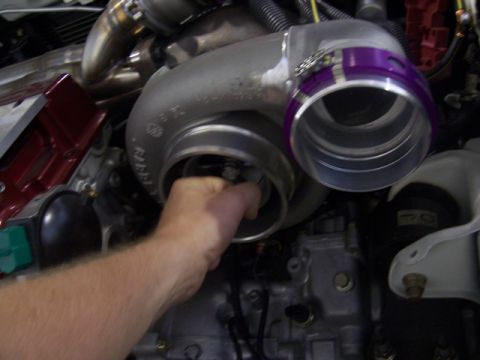 1990 Ford Probe - Close-up of a turbocharger being worked on, with a hand visible inside the intake housing.