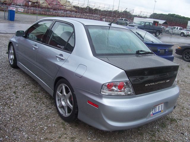 Silver Mitsubishi Lancer Evolution VIII with carbon fiber trunk, parked on gravel lot