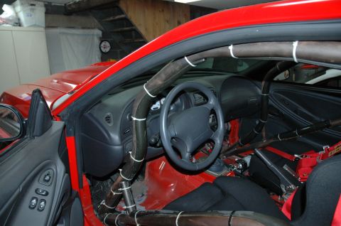 2000 Ford Mustang - Interior view of a red 2000 Ford Mustang equipped with a roll cage and racing seat.