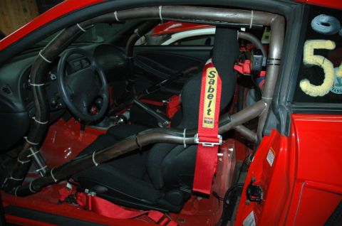 2000 Ford Mustang - Interior view of a red 2000 Ford Mustang, modified with a roll cage and racing seat for track use.