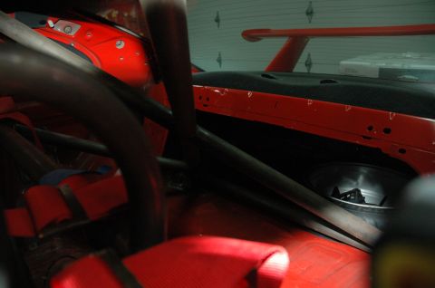 2000 Ford Mustang - Interior view of a car's cabin, a prominent roll cage and red racing seat.