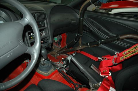 2000 Ford Mustang - The interior of a 2000 Ford Mustang shows a roll cage and racing seatbelts, indicating a focus on performance.