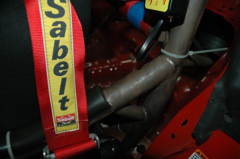 2000 Ford Mustang - Close-up of a red Sabelt racing harness and a metal roll cage, suggesting a performance-oriented interior.