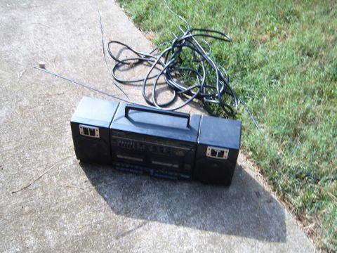 1988 Ford Bronco - Boombox with tangled cords on concrete and grass.