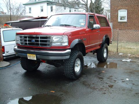 1994 Ford Bronco - This lifted 1994 Ford Bronco is shown in a three-quarter front view, parked on a wet surface.