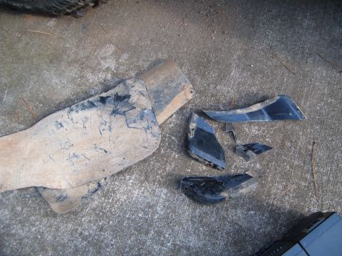 1988 Ford Bronco - Several pieces of broken black plastic fender trim lie on a concrete surface.