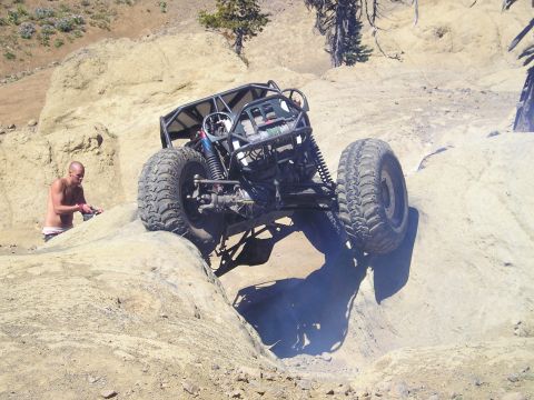 1989 Ford Bronco - A custom off-road buggy tackles a steep, rocky terrain with a person observing the action.