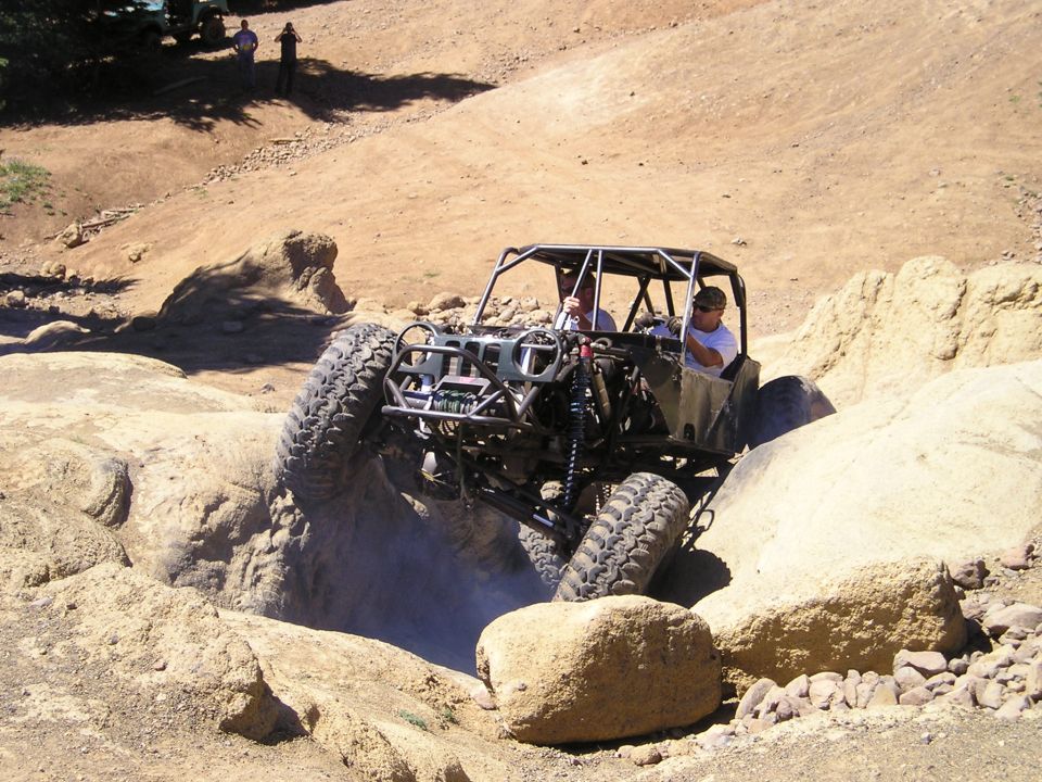 Custom off-road buggy with a roll cage navigating a rocky terrain