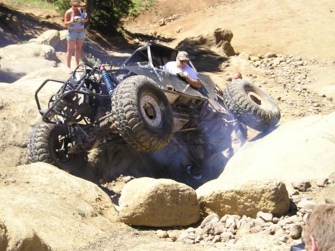 1989 Ford Bronco - Custom off-road buggy navigates a rocky trail, kicking up dust.