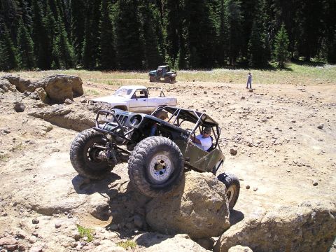 1989 Ford Bronco - Off-road vehicles navigate a rocky trail in a wooded area.