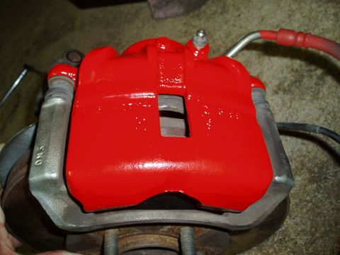1993 Ford Taurus - A freshly painted red brake caliper is shown, with visible text on the mounting bracket.
